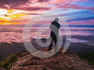 Traveler stand on Rocky cilff with sunsire sky and beautiful cloud sea on `Pa na rai` Khao Luang mountian