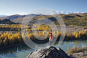 Traveler Standing and Hands Raising on the Rock and Looking at the Chuya River in Altai Mountains