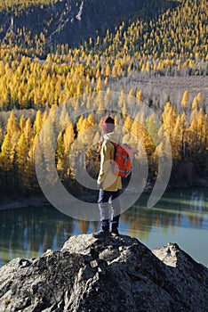 Traveler Standing on the Rock and Looking at the Golden Autumn in Altai Mountains  Russia
