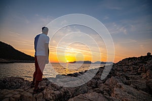 Traveler stands on the rock seashore