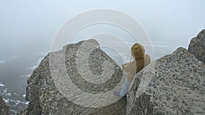 The traveler stands on a steep cliff at the foot of which the valley is partially covered with snow, which is covered