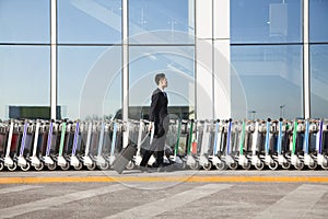 Traveler with suitcase next to row of luggage carts at airport