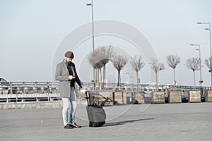 Traveler with suitcase waiting transportation to airport railway station. Ready to travel. Carry travel bag. Business