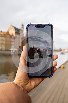 Traveler taking photo of Ancient crane - zuraw Old town in Gdansk. The riverside on Granary Island reflection in Moltawa