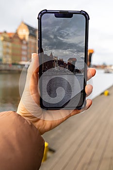 Traveler taking photo of Ancient crane - zuraw Old town in Gdansk. The riverside on Granary Island reflection in Moltawa