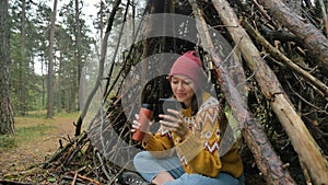 Traveler with thermos surfs internet with phone inside hut