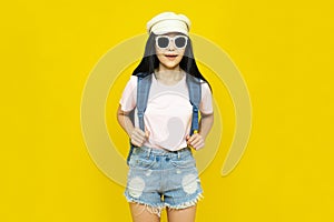 Traveler tourist beautiful young asian woman in casual clothes,cap and sunglasses with backpack isolated on yellow background.