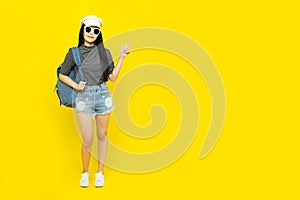 Traveler tourist beautiful young asian woman in casual clothes and sunglasses with Backpack Selfie isolated on yellow background.