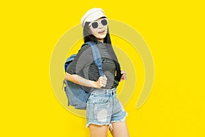 Traveler tourist beautiful young asian woman in casual clothes and sunglasses with Backpack Selfie isolated on yellow background.