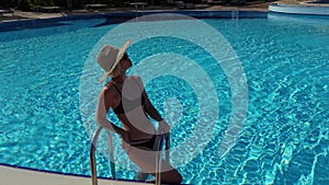 traveler tourist bikini woman in hat relaxing vacation happy holiday at luxury hotel tropical resort swimming pool