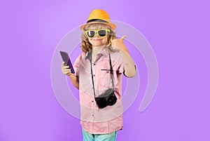 Traveler tourist kid boy. Kid boy with mobile phone. Kid tourist with smartphone and camera on blue studio isolated