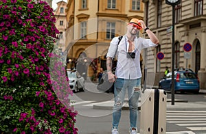 Traveler tourist man in casual clothes hat with suitcase. Man traveler with travel bag outdoor. Portrait of young