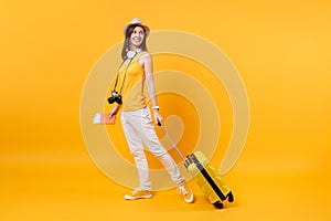 Traveler tourist woman in summer casual clothes, hat with headphones on neck isolated on yellow orange background photo