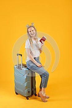 Traveler tourist woman in summer casual clothes hat sit with suitcase isolated on yellow orange background