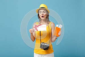 Traveler tourist woman in yellow casual clothes hat hold tickets gift card camera isolated on blue background. Female