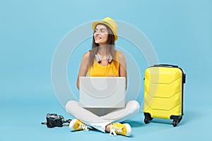 Traveler tourist woman in yellow casual clothes, hat with suitcase laptop pc photo camera isolated on blue background