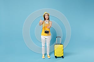 Traveler tourist woman in yellow summer casual clothes hat hold tickets bag camera isolated on blue background. Female
