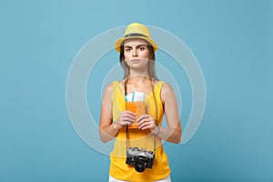 Traveler tourist woman in yellow summer casual clothes hat hold tickets camera isolated on blue background. Female