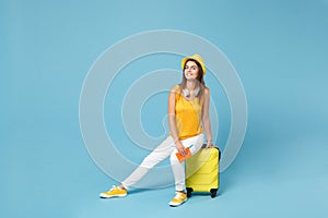 Traveler tourist woman in yellow summer casual clothes hat hold tickets luggage isolated on blue background. Female