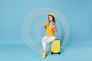 Traveler tourist woman in yellow summer casual clothes hat hold tickets luggage isolated on blue background. Female