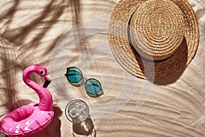 Traveler vacation accessories are laid out on a white beach sand. Flat lay, top view.