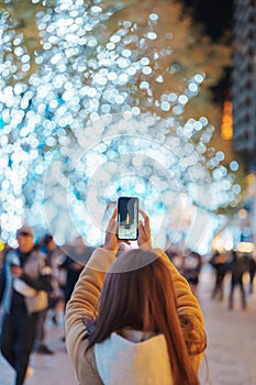 Traveler visiting Roppongi Hills Christmas Illumination and taking photo Tokyo tower, happy tourist woman stands on a christmas