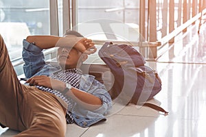 Traveler waiting at the airport departure area for his delay flight.  Young traveler sleeping on the floor with his baggage, stuff