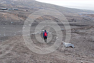 Traveler walking through the desert volcanic terrain, the foot of the mountains