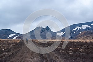 Traveler walking through the desert volcanic terrain, the foot of the mountains, volcanic