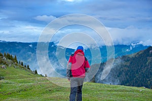 Traveler walks through the alpine meadow to the cliff