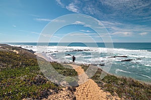 Traveler walks on a sandy path during a sunny day in Odemira region, western Portugal. Wandering along the Fisherman Trail, Rota photo