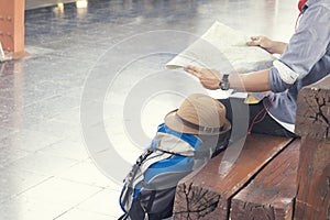 Traveler wearing backpack holding map, waiting for a train at trainstation and planing for next trip. photo
