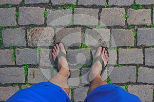 Traveler wearing in flip-flops is walking on a paved path