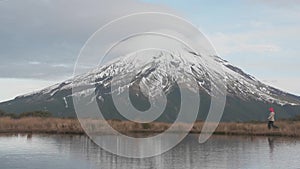 Traveler wlking to the view looking to the taranaki volcano in the north island of new zealand and with the reflection