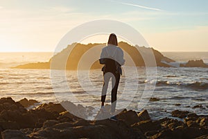 Traveler woman with backpack enjoying ocean view, girl hiker at sunset, travel concept, California, USA