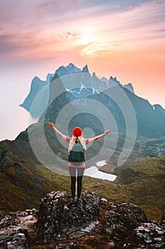 Traveler woman with backpack hiking in Norway girl raised arms alone on mountain top outdoor travel summer vacations