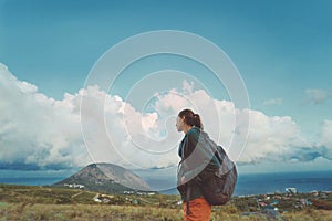 Traveler woman with backpack relaxing and enjoing serene view mountain, sky and seascape. Travel Lifestyle wanderlust