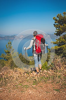 Traveler woman with backpack stands on the cliff