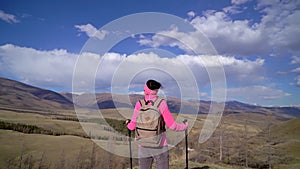 traveler woman with backpack and trekking poles enjoying on top of mountain