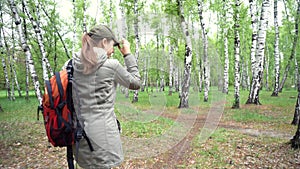 Traveler woman with backpack walking on path in forest