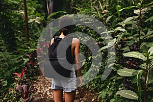 Traveler woman with backpack walking on path in jungle tropical deep forest,