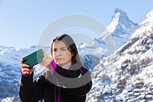 Traveler woman capturing scenic mountain views from mobile phone