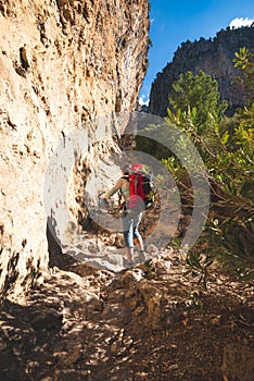 Traveler woman climbs along narrow mountain gorge