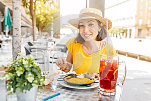 Traveler woman eating spanish dinner sea Paella and sangria fruit wine during siesta