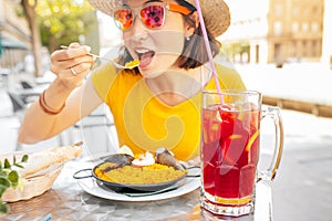 Traveler woman eating spanish dinner sea Paella and sangria fruit wine during siesta