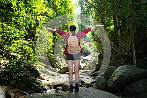 Traveler woman feeling victorious facing on the waterfall.