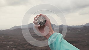 Traveler woman hand with a compass in the mountains.
