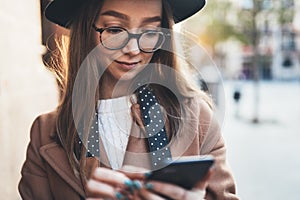 Traveler woman in hat hold in hands mobile phone. Closeup smartphone technology internet online. Girl tourist in glasses