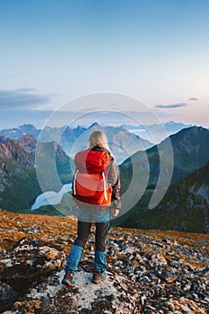 Traveler woman hiking in Norway solo in mountains of Lofoten islands girl tourist with red backpack traveling outdoor