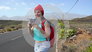 Traveler woman hitchhiking on a sunny road and walking. Backpacker woman looking for a ride to start a journey on a